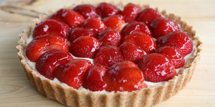 close-up of a homemade strawberry tart with jam glazing against a wood background taken by a canon 5d