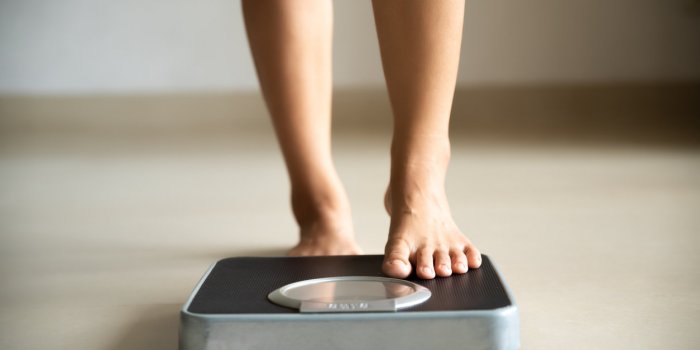 female leg stepping on weigh scales healthy lifestyle, food and sport concept