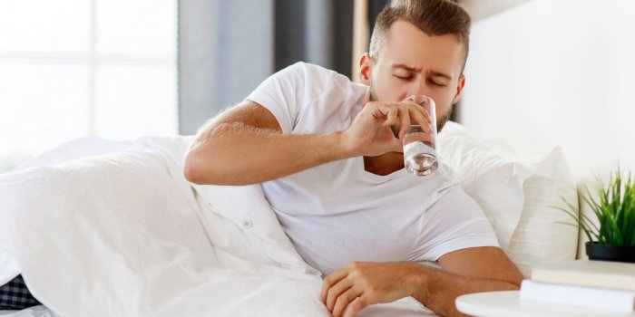 young healthy man drinking water in morning at window