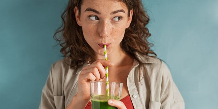 beautiful woman drinking an organic green smoothie fit young woman drinking detox juice using paper straw isolated agains...