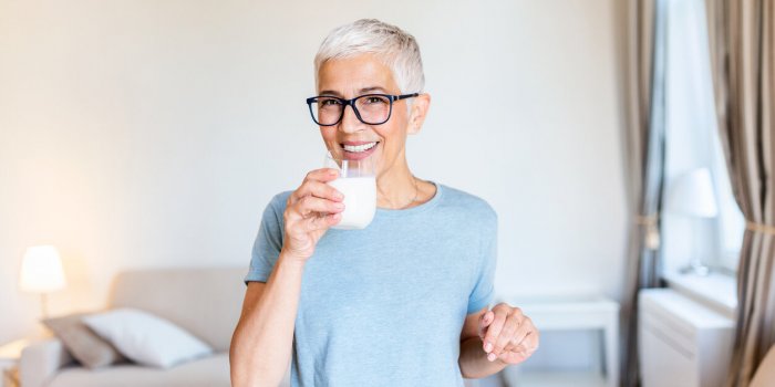 senior woman's hands holding a glass of milk happy senior woman having fun while drinking milk at home senior woman drink...