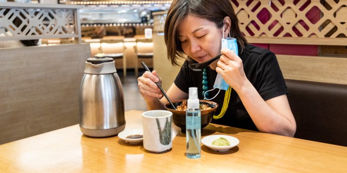 asian women having meal with facemask and sanitizer, with social distancing in malaysia