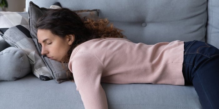 tired unmotivated young woman falls asleep on cozy couch indoors, having no energy after hard working day exhausted cauca...