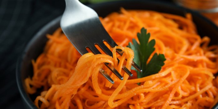 fork with korean carrot salad over bowl, closeup
