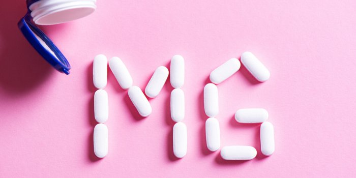 mineral pill capsule magnesium white vitamin pills forming shape to mg sign and plastic bottle on pink background, copy s...