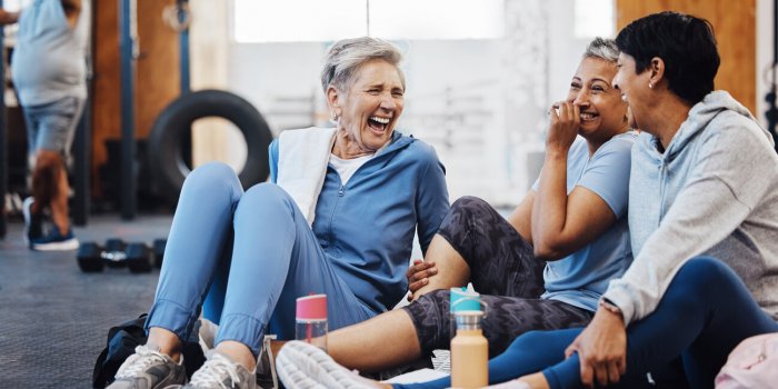 gym, laughing and group of mature women telling joke after fitness class, conversation and comedy on floor exercise, bond...