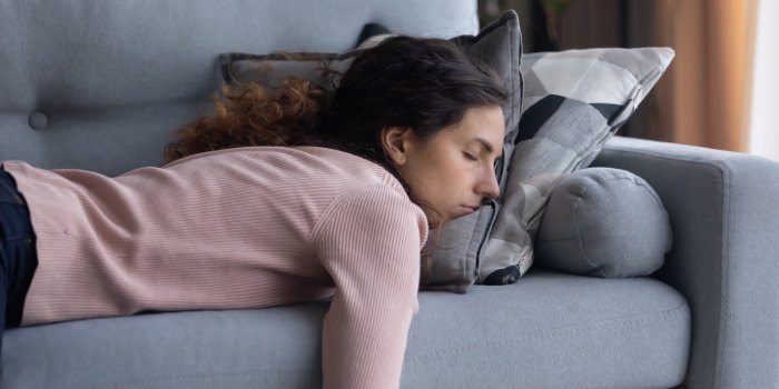 exhausted young caucasian woman lying on comfortable sofa in living room sleeping after hard-working day, tired millennia...