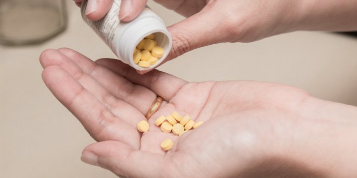 woman holding medicines bottle and pouring some pills on another hand for treatment medication
