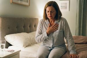 Photo d'une personne sur le point de se coucher et qui se touche le haut de la poitrine pour signifi