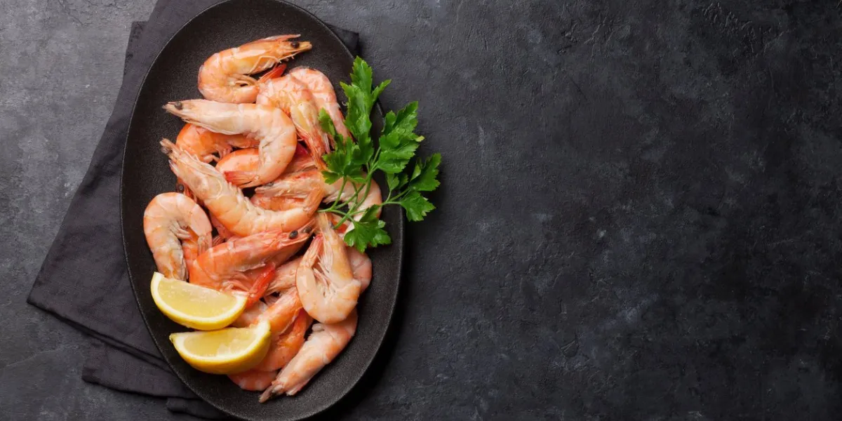 steamed tiger shrimps with parsley and lemon top view with copy space for your text