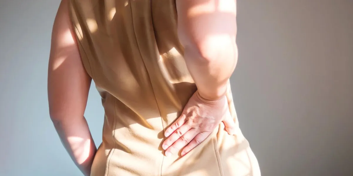 woman holding two hands on back back pain at waist symptoms of office syndrome healthcare background