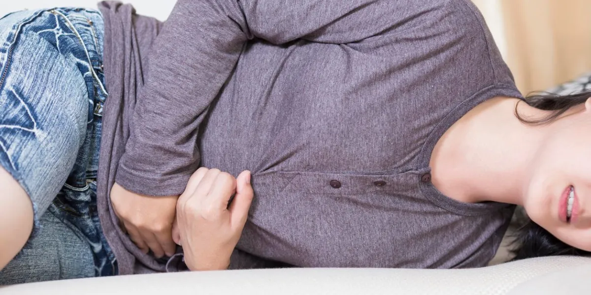 woman suffering from stomachache on sofa