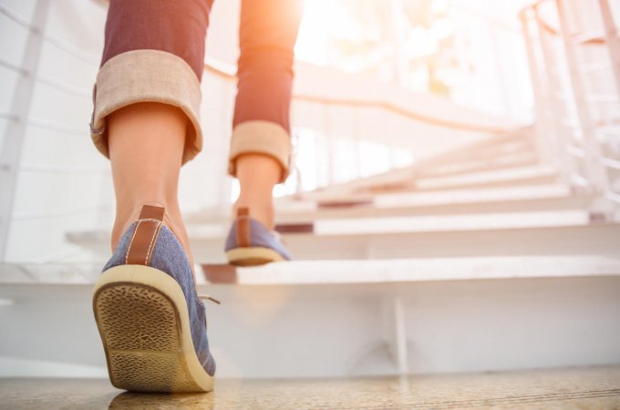 young adult woman walking up the stairs with sun sport background