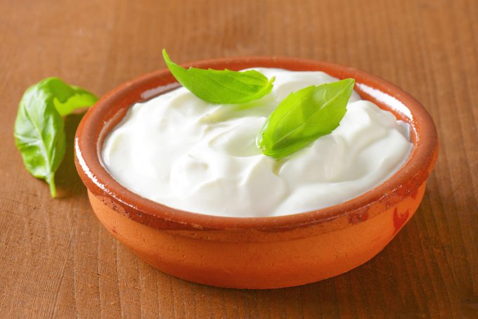 bowl of white cream on wooden table - close up