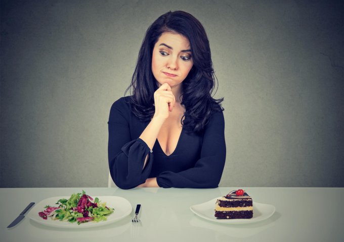 dieting concept, beautiful young woman choosing between healthy food and tasty cake