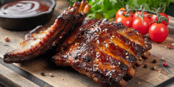 closeup of pork ribs grilled with bbq sauce and caramelized in honey tasty snack to beer on a wooden board for filing on ...