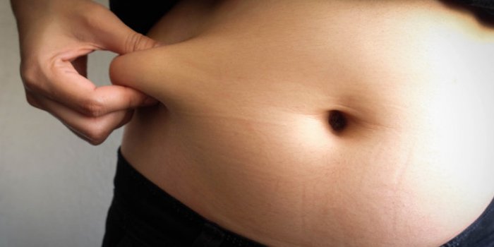 woman hand catching fat body belly paunch , diabetic risk factor