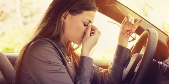 business woman having headache taking off her glasses has to make a stop after driving car in traffic jam on rush hour ex...
