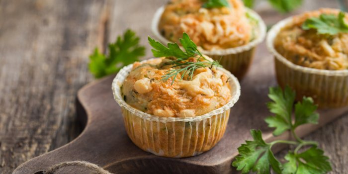 savory muffins with zucchini and cheese on wooden background