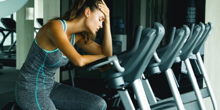 woman on the stationary bike with overtraining symptoms