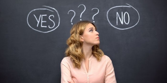 uncertain female choosing between yes no, standing against blackboard, dilemma