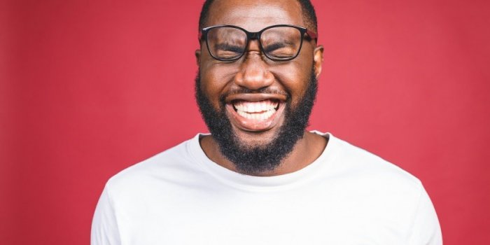 portrait of african american man laughing isilated over red
