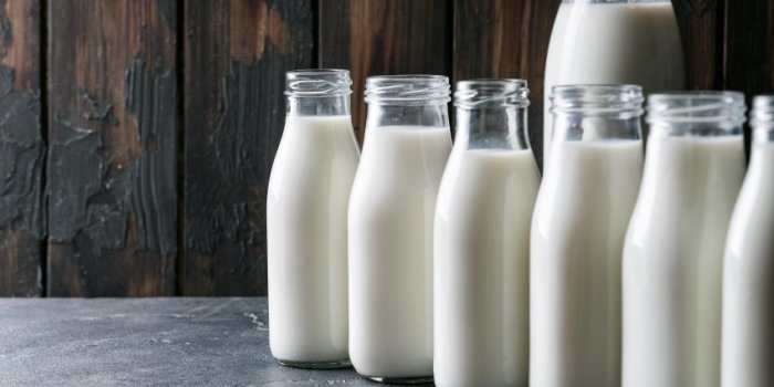 fresh milk in different glass bottles standing over dark wooden background eco friendly shopping concept