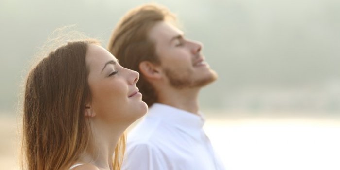 profile of a couple of man and woman breathing deep fresh air together at sunset