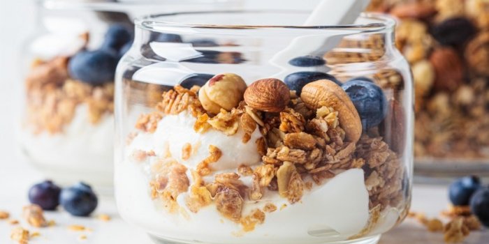 granola with nuts, yogurt and berries in a jar breakfast parfait with muesli, yoghurt and blueberries, white background
