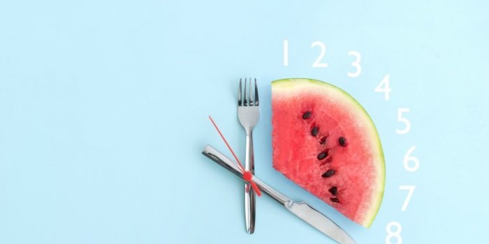watermelon with cutlery as clock hands, eight hour intermittent fasting diet concept