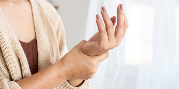 woman suffering from wrist pain, numbness, or carpal tunnel syndrome hand holding her ache joint