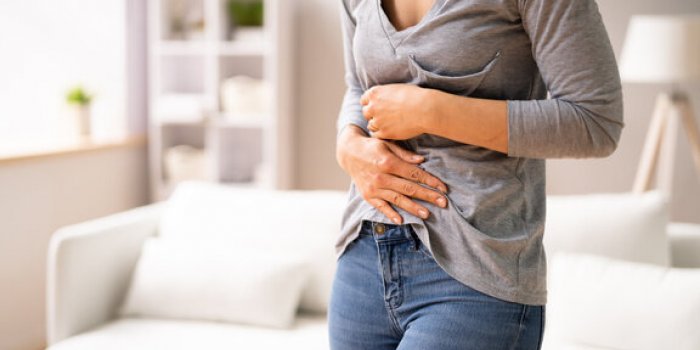 woman sitting on sofa suffering from stomach pain