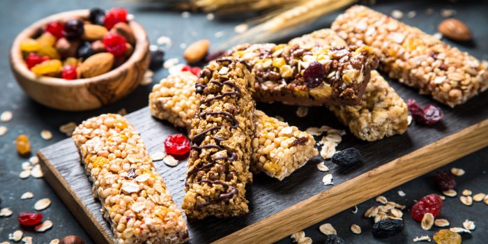 granola bar with nuts, fruit and berries on cutting board at dark stone table