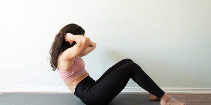 profile view of a fit young woman with curly hair doing sit up exercises for her home workout