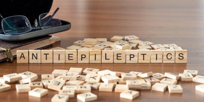 antiepileptics concept represented by wooden letter tiles on a wooden table with glasses and a book
