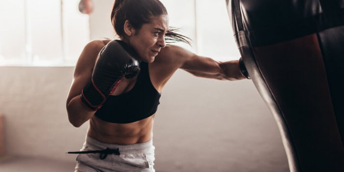 female boxer hitting a huge punching bag at a boxing studio woman boxer training hard