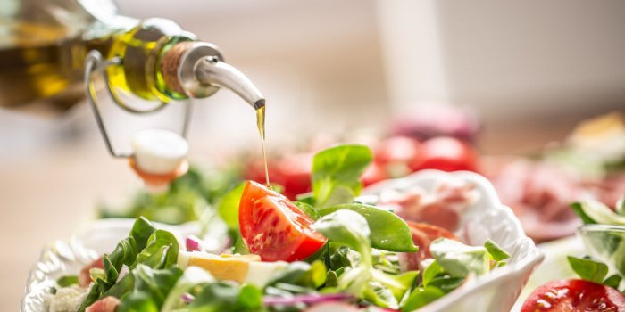 bottle with olive oil pouring into salad