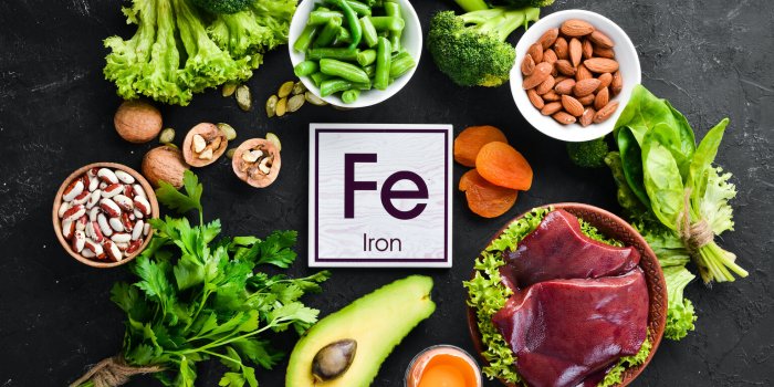 food containing natural iron fe liver, avocado, broccoli, spinach, parsley, beans, nuts, on a black stone background top...