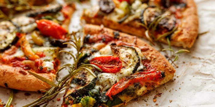 vegetarian pizza with addition grilled vegetables and aromatic herbs, divided into portions
