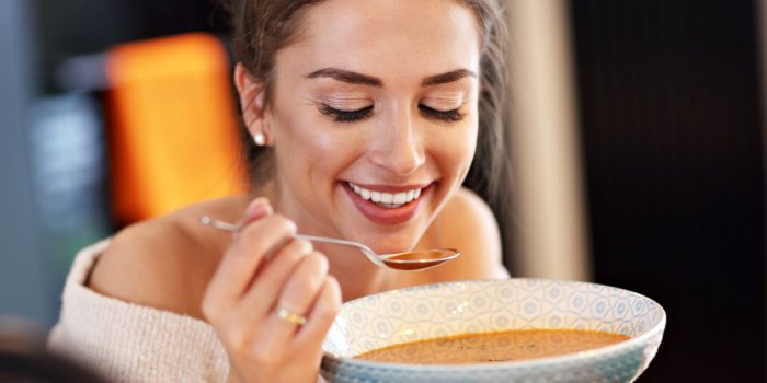 picture of adult woman tasting pumpkin soup in the kitchen