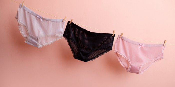colorful clean women's panties hang on a rope on a pink isolated background