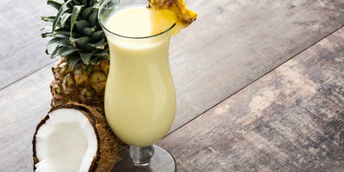 piÃ±a colada cocktail and pineapple fruit on wooden background