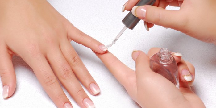 female hands painting a woman's nails with clear varnish