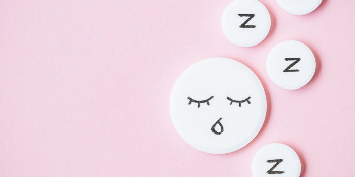 top view of sleeping pills with drawn face and z signs on pink