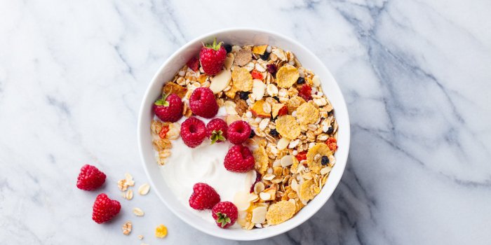 healthy breakfast fresh granola, muesli with yogurt and berries on marble background top view