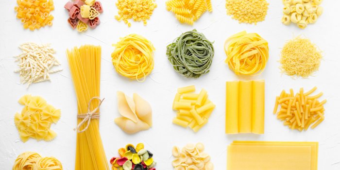 variety of types and shapes of italian pasta in rows on white background from above italian cuisine food concept and menu...