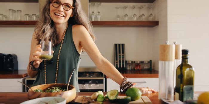 healthy senior woman smiling while holding some green juice in her kitchen mature woman serving herself wholesome vegan f...