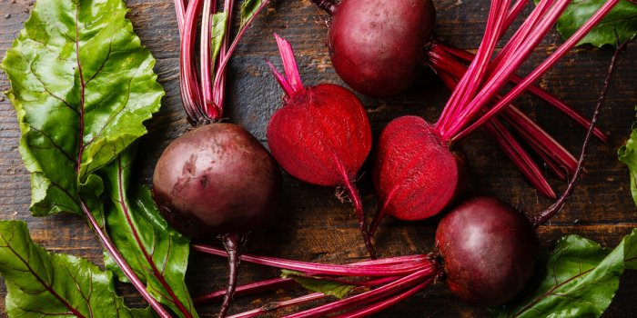 red beetroot with herbage green leaves on wooden background
