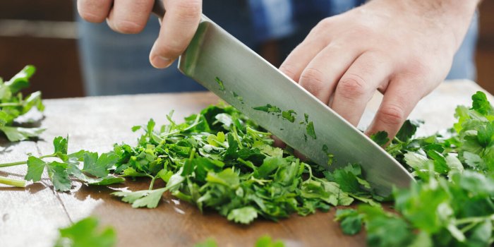 man is cooking parsley on wooden table close up