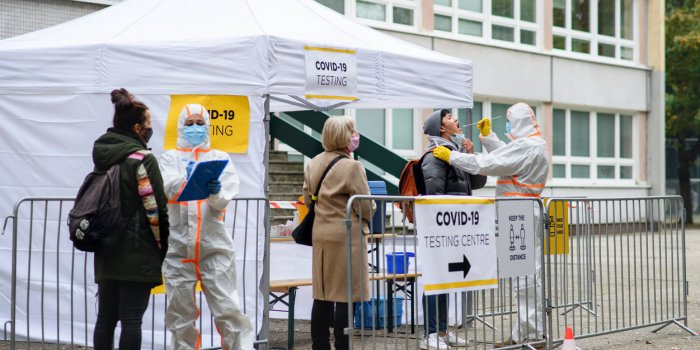 people waiting in covid-19 testing center outdoors on city street, coronavirus concept